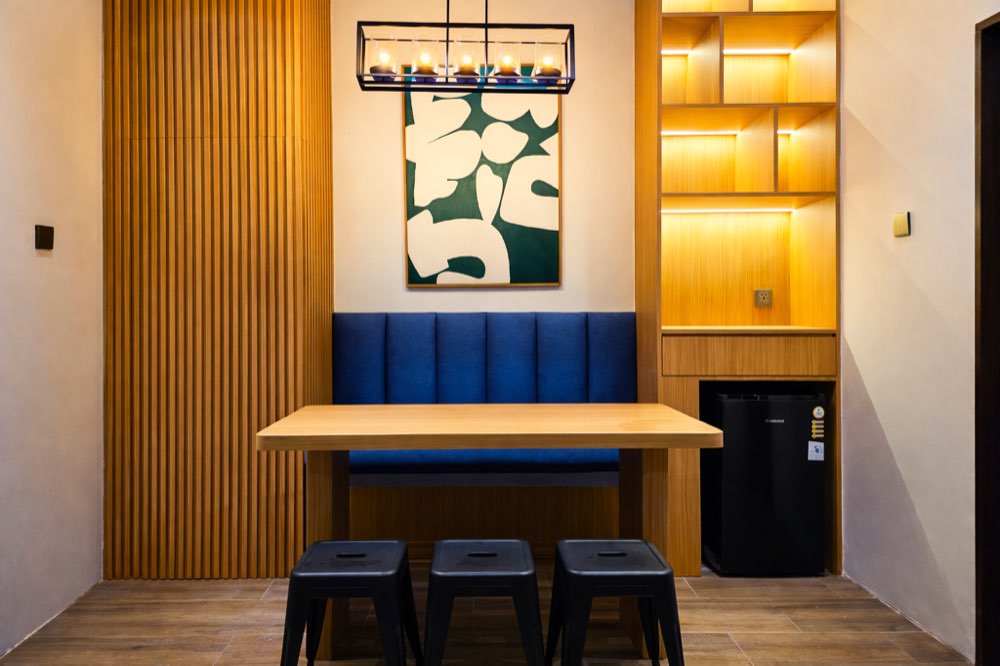 Dining nook with a blue bench, a wooden table and a lit shelf