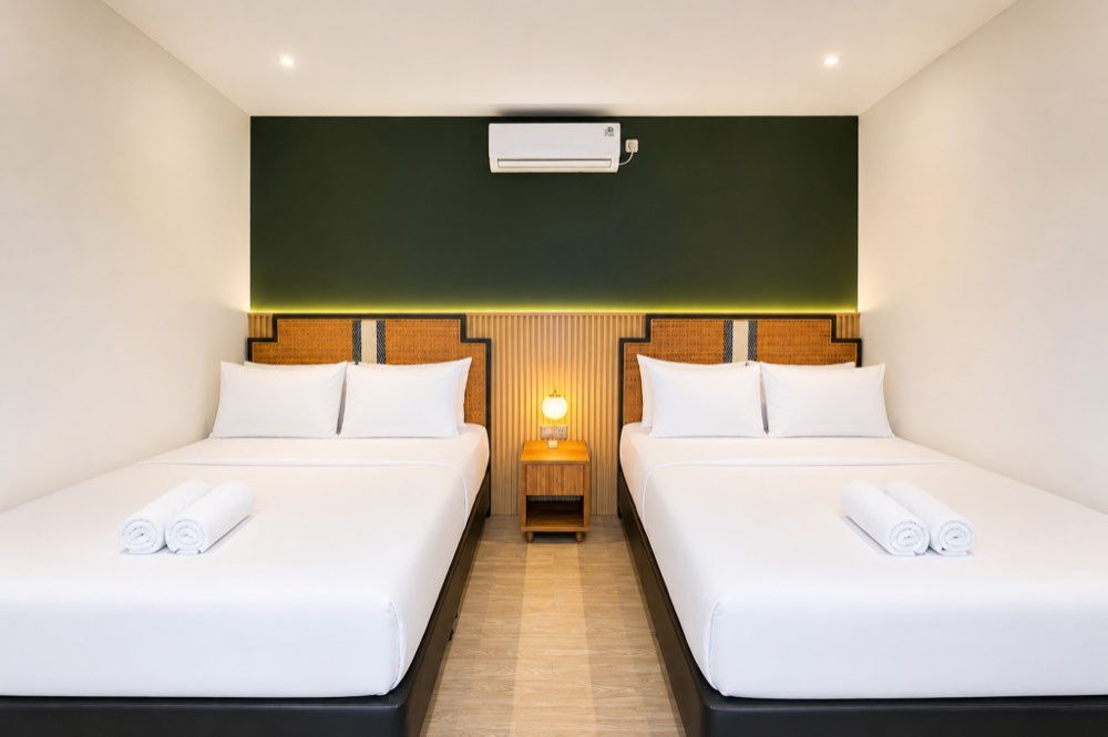 Two beds side by side under a dark green wall