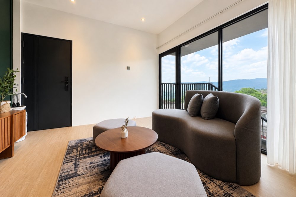 Living room with a curved grey sofa and a window onto the hills