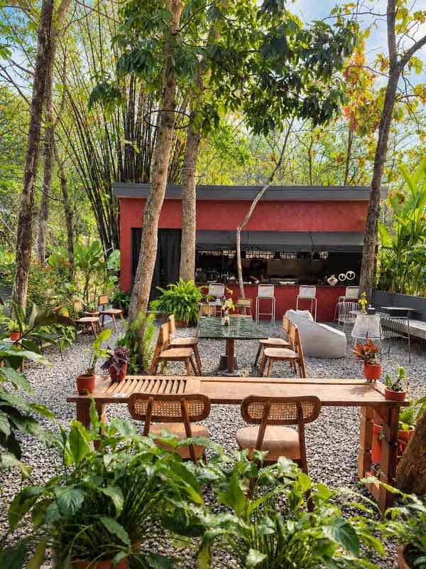 Wooden dining tables and rattan chairs in the garden in front of Dapur Guri
