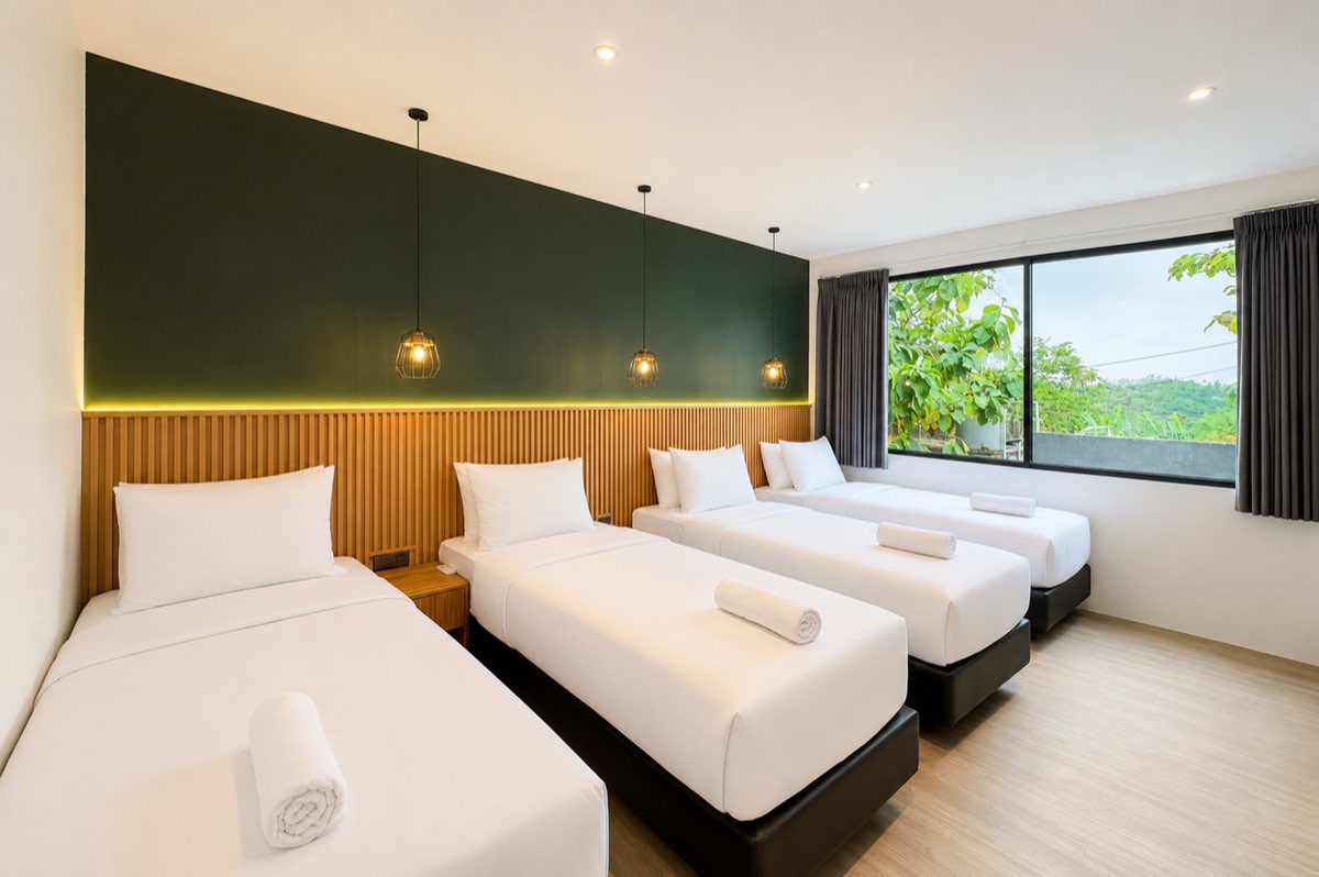 Bedroom with four single beds against a dark green wall