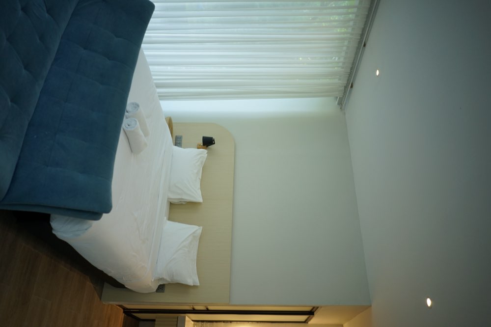 King bed with a blue velvet sofa at its foot