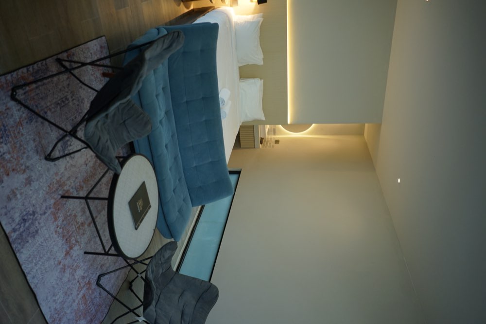 Bed, blue sofa and two butterfly chairs around a round coffee table