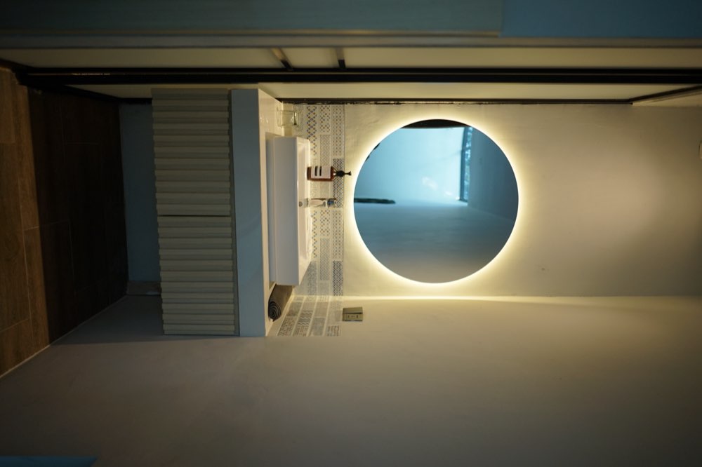 Round backlit mirror over a white basin