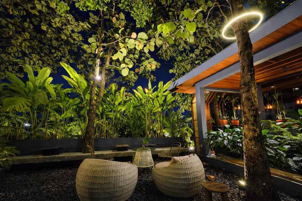 Rattan seats lit by a ring lamp in the garden at night
