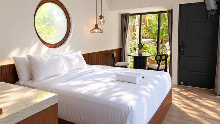 King bed under a round window, with pendant lights
