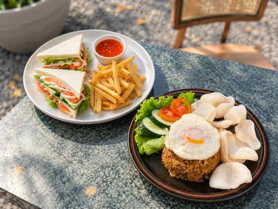 A sandwich with fries and a plate of fried rice with crackers and drinks